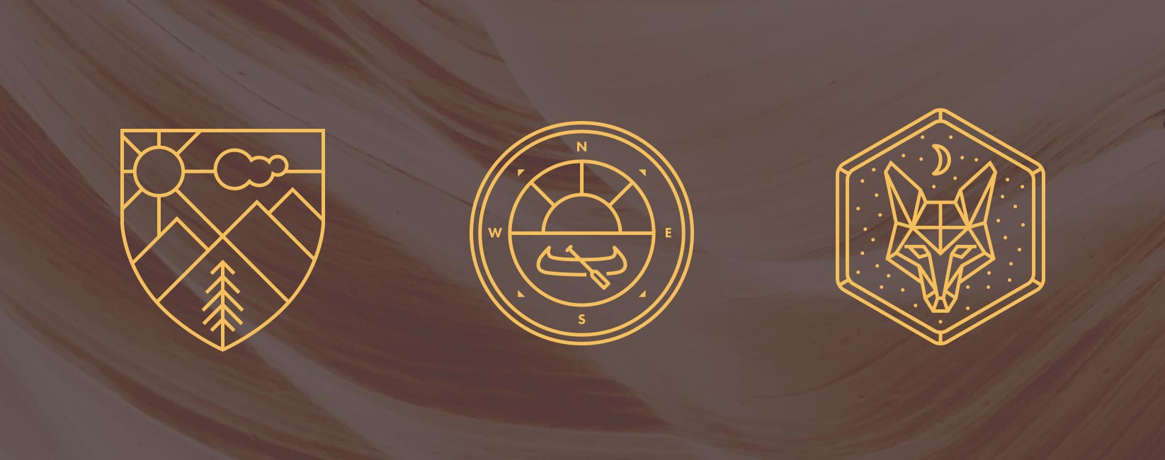 Three gold line-art badges on a dark ground: a mountain shield, a canoe compass, and a fox under stars